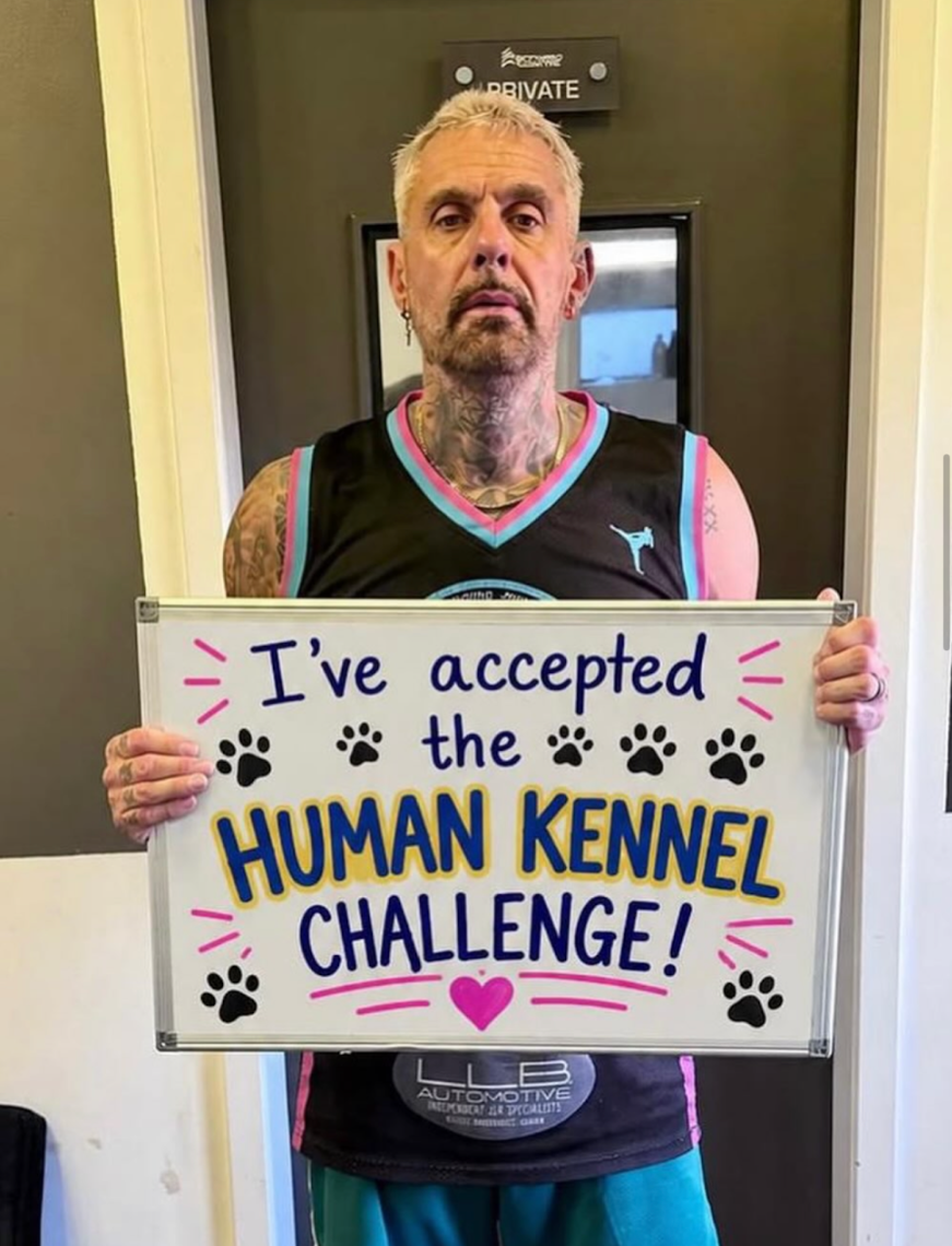 Paul Dash holding his "I've accepted the Human Kennel Challenge" board