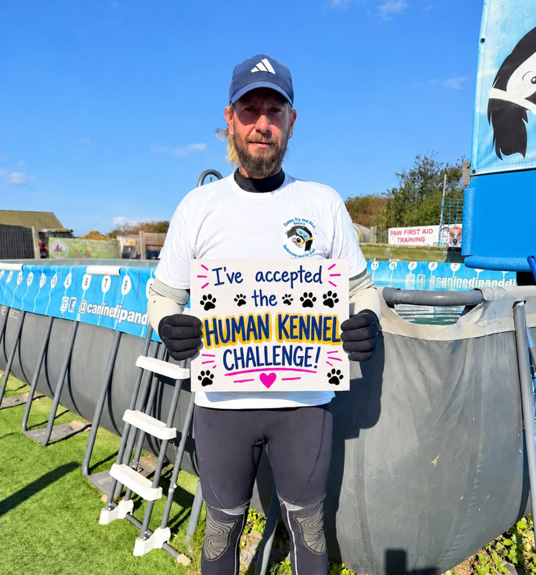 Terry from Canine Dip and Dive holding his "I've accepted the Human Kennel Challenge" board