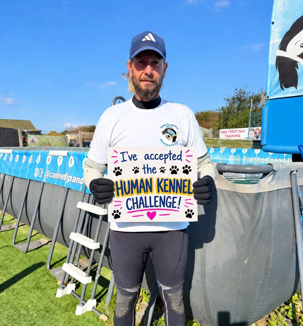 Terry from Canine Dip and Dive holding his "I've accepted the Human Kennel Challenge" board